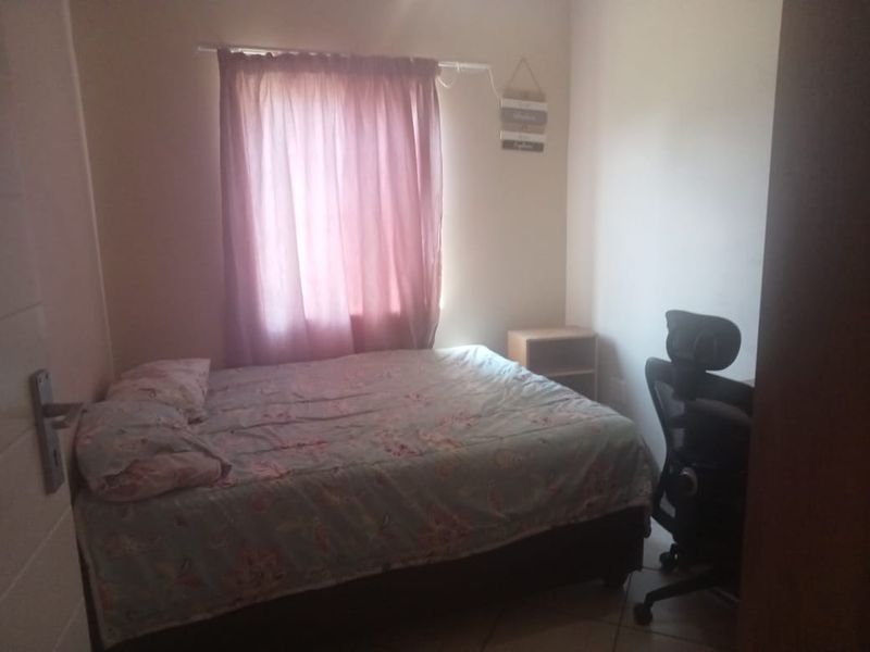 A standard bedroom featuring tiled flooring and a window with curtain treatments.