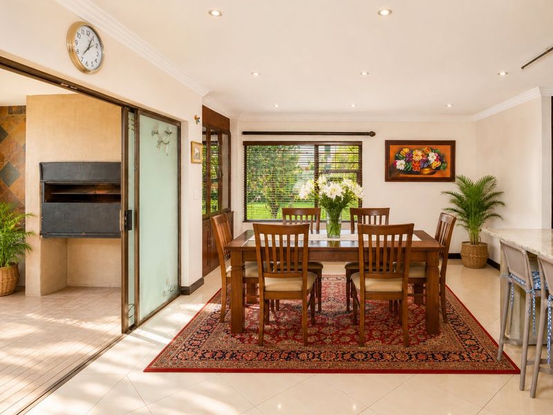 Spacious dining area featuring tiled floors, recessed lighting, and seamless access to an indoor braai room through sliding glass doors.
