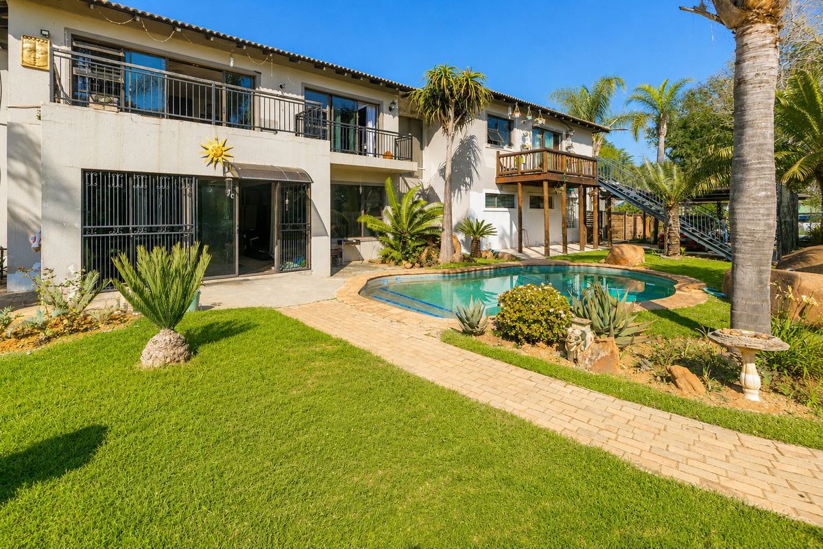 Rear exterior view featuring a swimming pool, landscaped garden, paved walkway, and a two-story building with balconies and metal staircase access.
