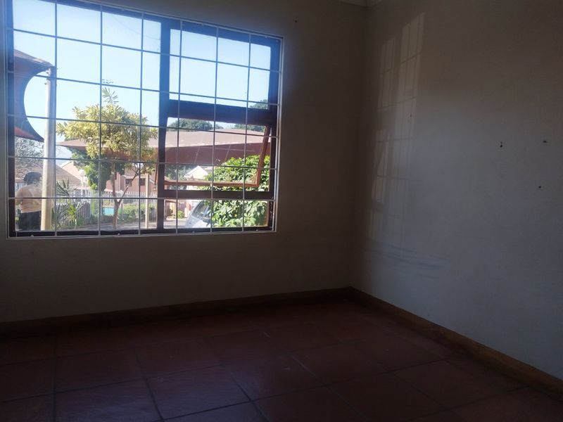 An empty bedroom featuring tiled flooring and a window fitted with security bars, offering a blank canvas for personalization.