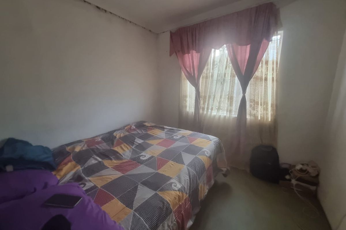A bedroom featuring a window with security bars, showing signs of ceiling water damage and requiring maintenance to the wall and ceiling finishes.