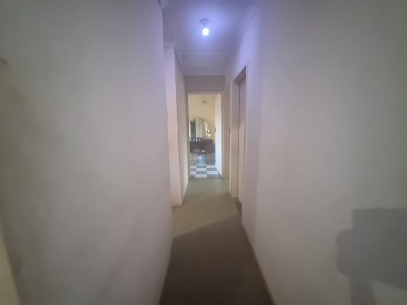 A simple interior hallway connecting multiple rooms, featuring plain walls and standard internal door frames.