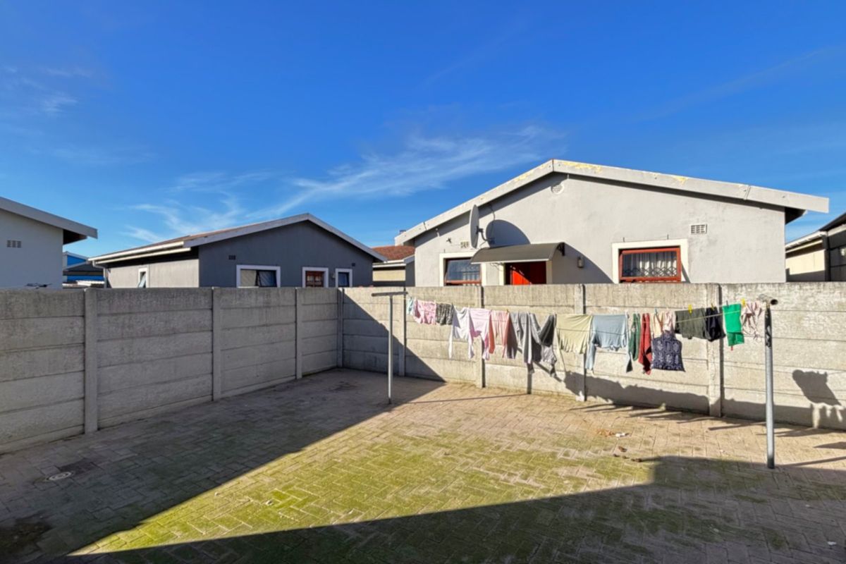 A rear courtyard featuring paved flooring and a precast concrete boundary wall, providing a private outdoor space.