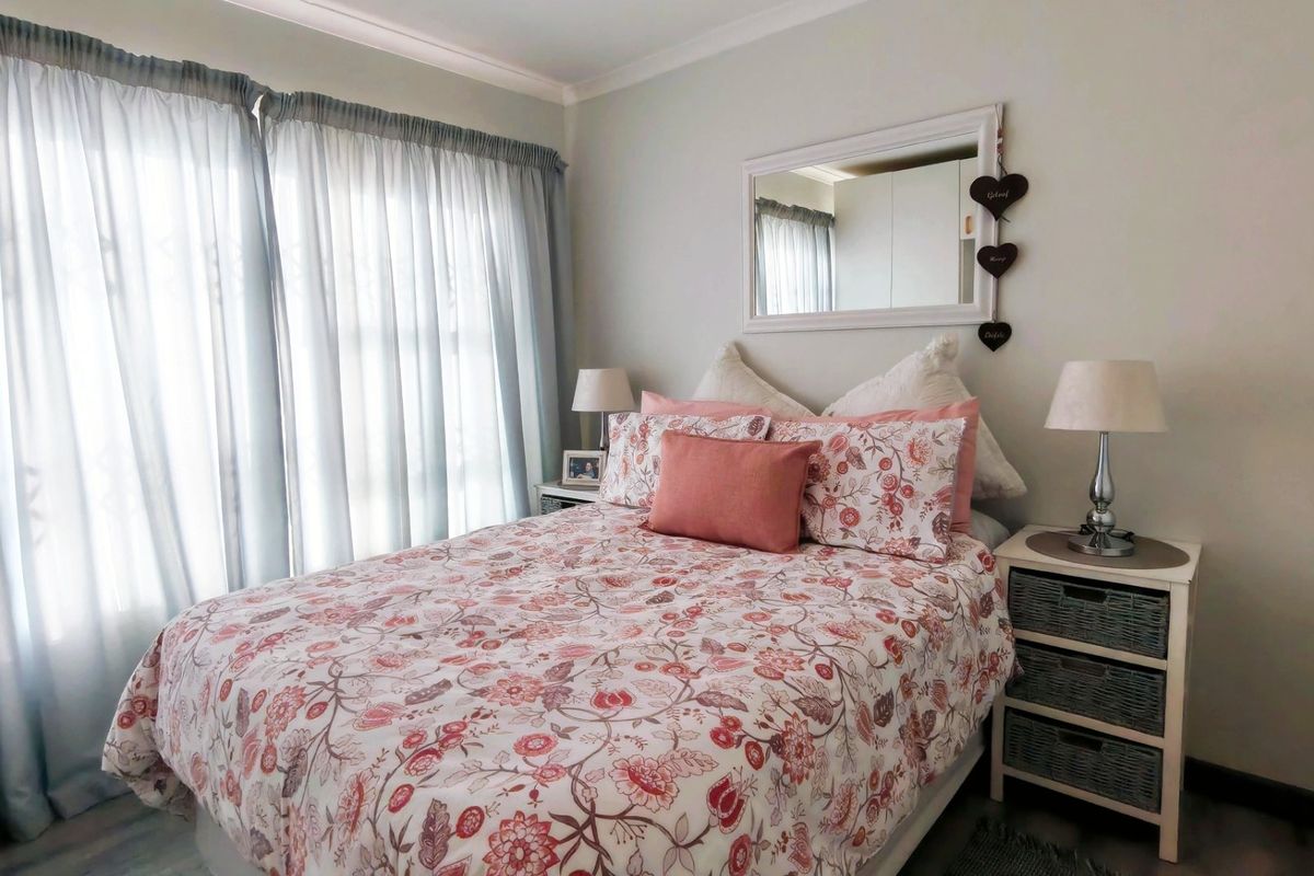A well-maintained bedroom featuring neutral walls, cove cornicing, and a large sliding glass door that provides ample natural light.