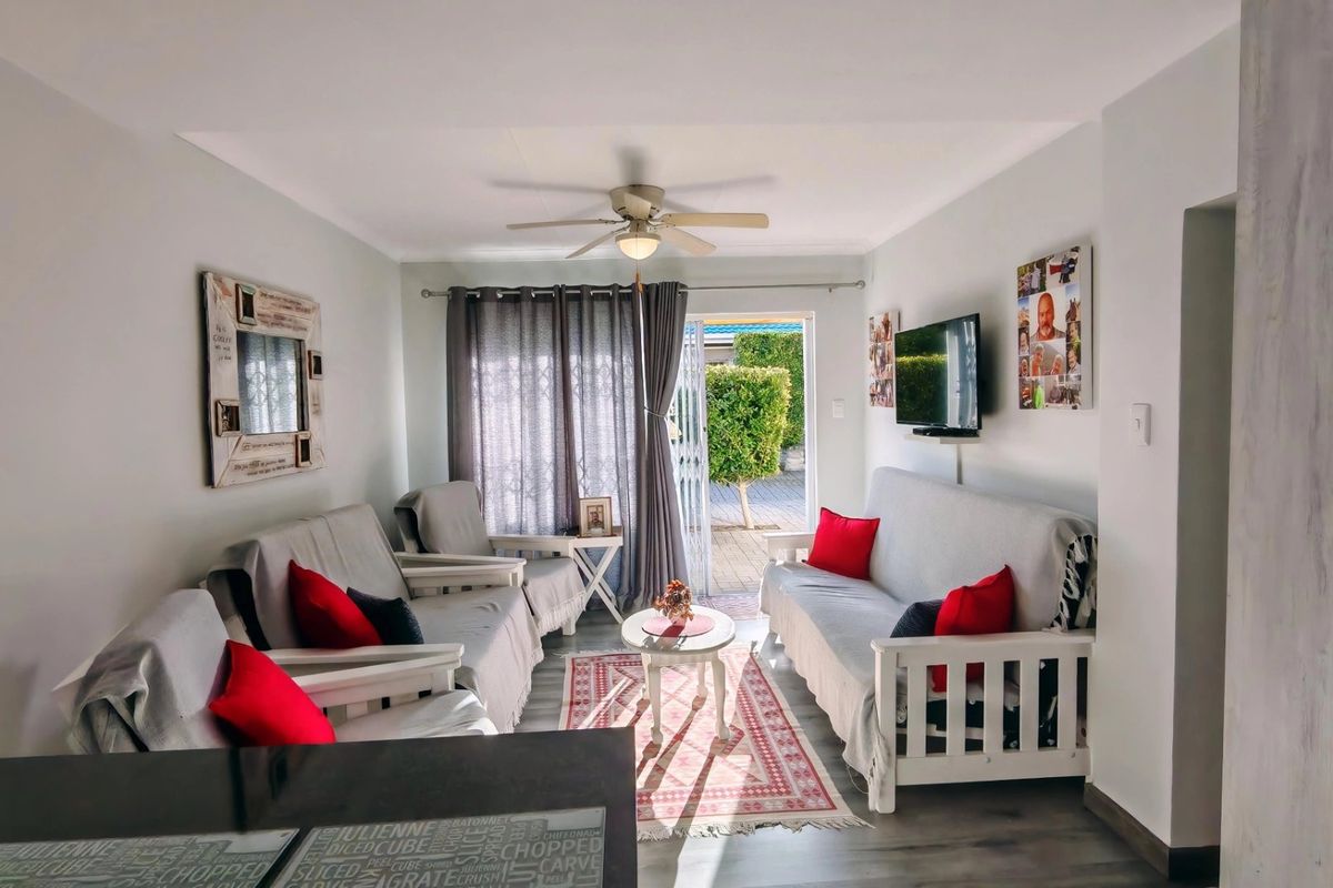 A comfortable living room featuring laminate flooring, a ceiling fan, and a sliding glass door providing direct access to the outdoor patio area.