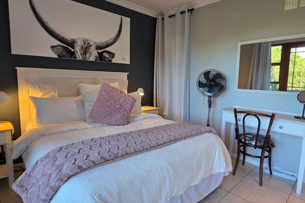 A well-maintained bedroom featuring tiled flooring, neutral wall tones, and a large window providing natural light.