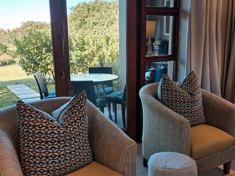 A comfortable living area featuring large timber-framed sliding doors that provide seamless access to an outdoor patio and garden space.