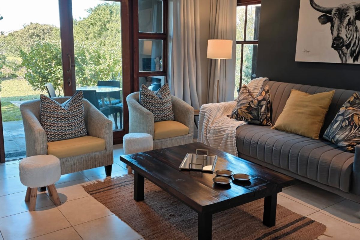 A well-lit living room featuring tiled flooring and large glass sliding doors that provide direct access to the outdoor garden area.