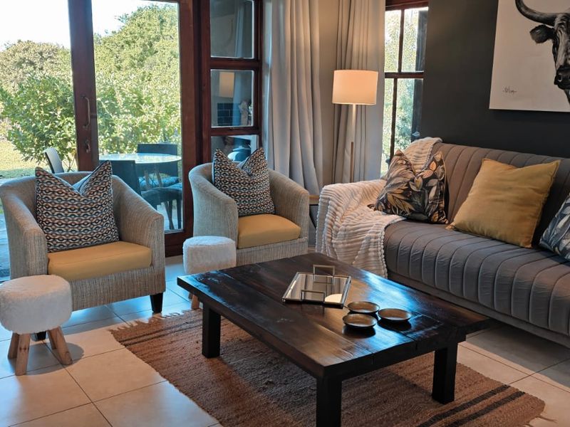 A well-lit living room featuring tiled flooring and large glass sliding doors that provide direct access to the outdoor garden area.