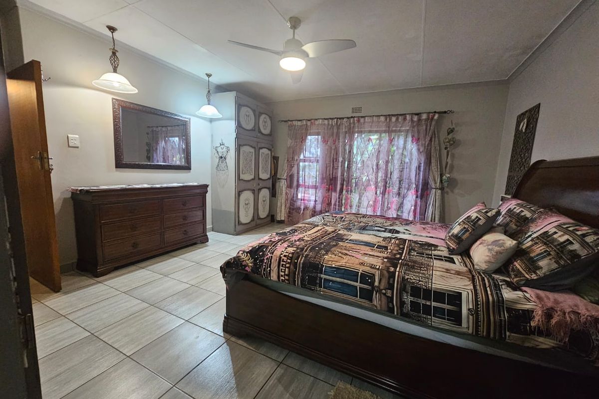 Spacious bedroom featuring tiled flooring, a ceiling fan, and built-in cupboard storage with direct access to the exterior via a sliding door.