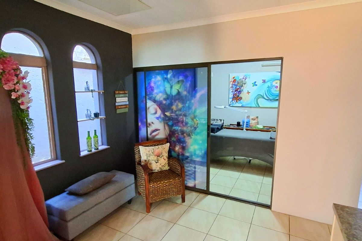 Living area featuring arched windows, tiled flooring, and a sliding glass door leading to an adjacent room.