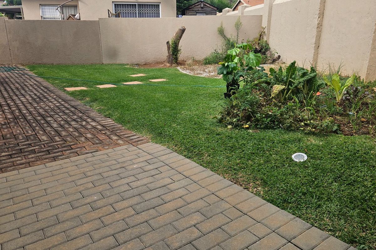 A private rear garden featuring a paved patio area, established lawn, and perimeter walling, offering potential for landscaping and outdoor living improvements.