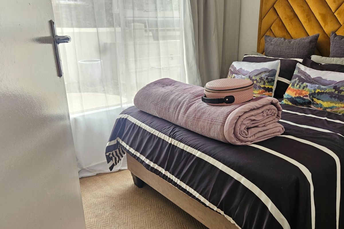 A cozy bedroom featuring neutral carpeted flooring and a sliding door providing access to an outdoor area.