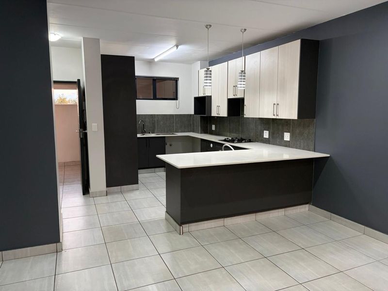 Modern kitchen featuring two-tone cabinetry, stone countertops, a gas hob, and tiled flooring in an open-plan layout.