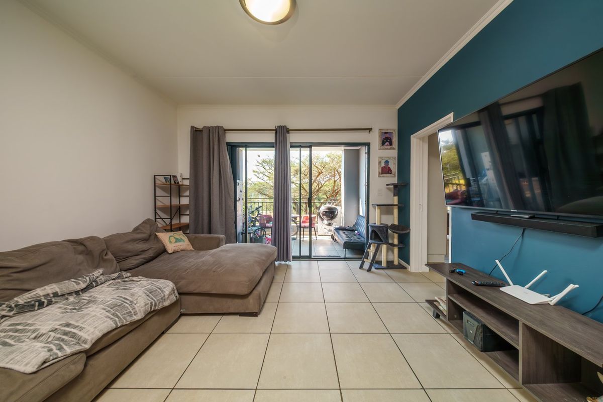 Spacious living room featuring neutral tiled flooring, a bold blue accent wall, and large sliding glass doors providing access to the outdoor patio area.