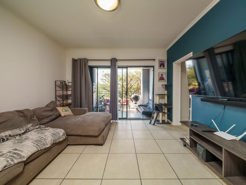 Spacious living room featuring neutral tiled flooring, a bold blue accent wall, and large sliding glass doors providing access to the outdoor patio area.