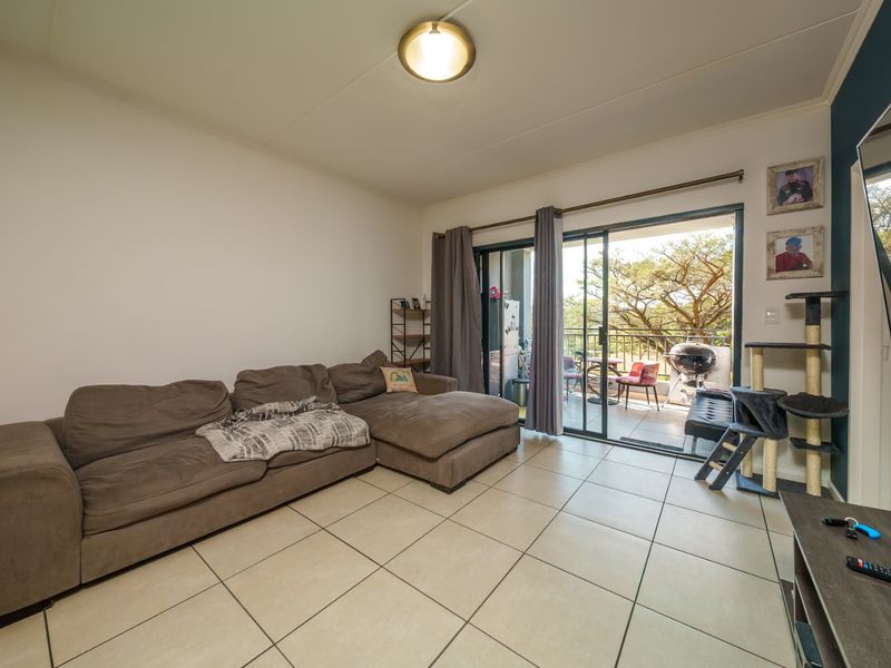 A living room featuring tiled flooring and a large sliding glass door providing access to an outdoor balcony area.