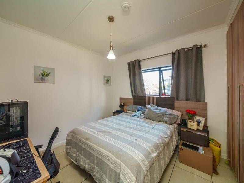 A functional bedroom featuring tiled flooring, a built-in wardrobe, and a top-hung window, providing a practical living space.