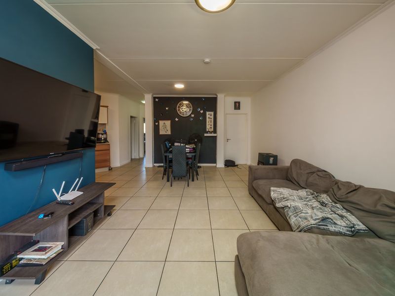 Open plan living and dining area featuring neutral tiled flooring and a bold blue accent wall.
