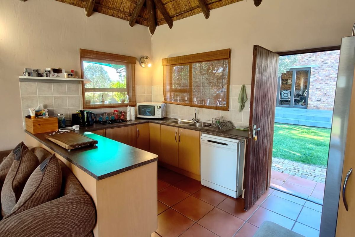 A compact kitchen featuring laminate countertops, built-in cabinetry, and a tiled backsplash, with direct access to the outdoor garden area.