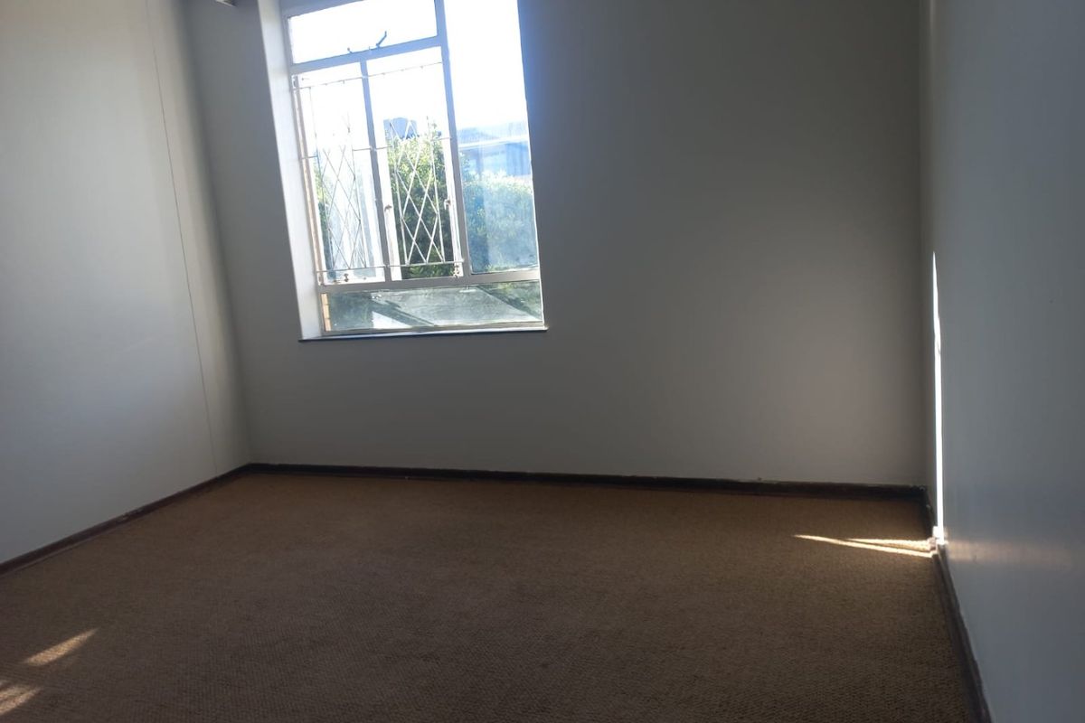 An empty bedroom featuring carpet flooring and a window fitted with security bars, offering a blank canvas for potential updates.