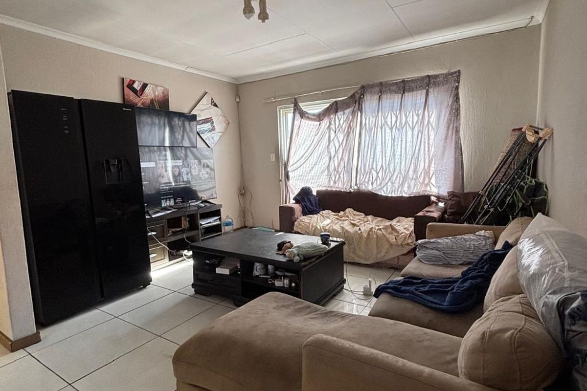 A living room featuring tiled flooring and a security gate, showing visible signs of ceiling water damage.