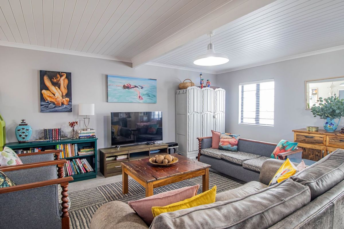 A comfortable living room featuring a white tongue and groove ceiling, neutral wall tones, and natural light through a standard window.