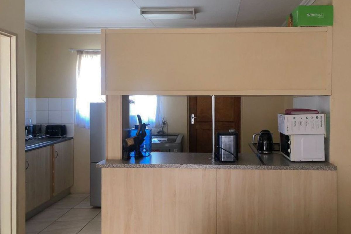 A functional kitchen featuring laminate cabinetry, a tiled backsplash, and a breakfast bar counter, providing a practical layout for daily meal preparation.