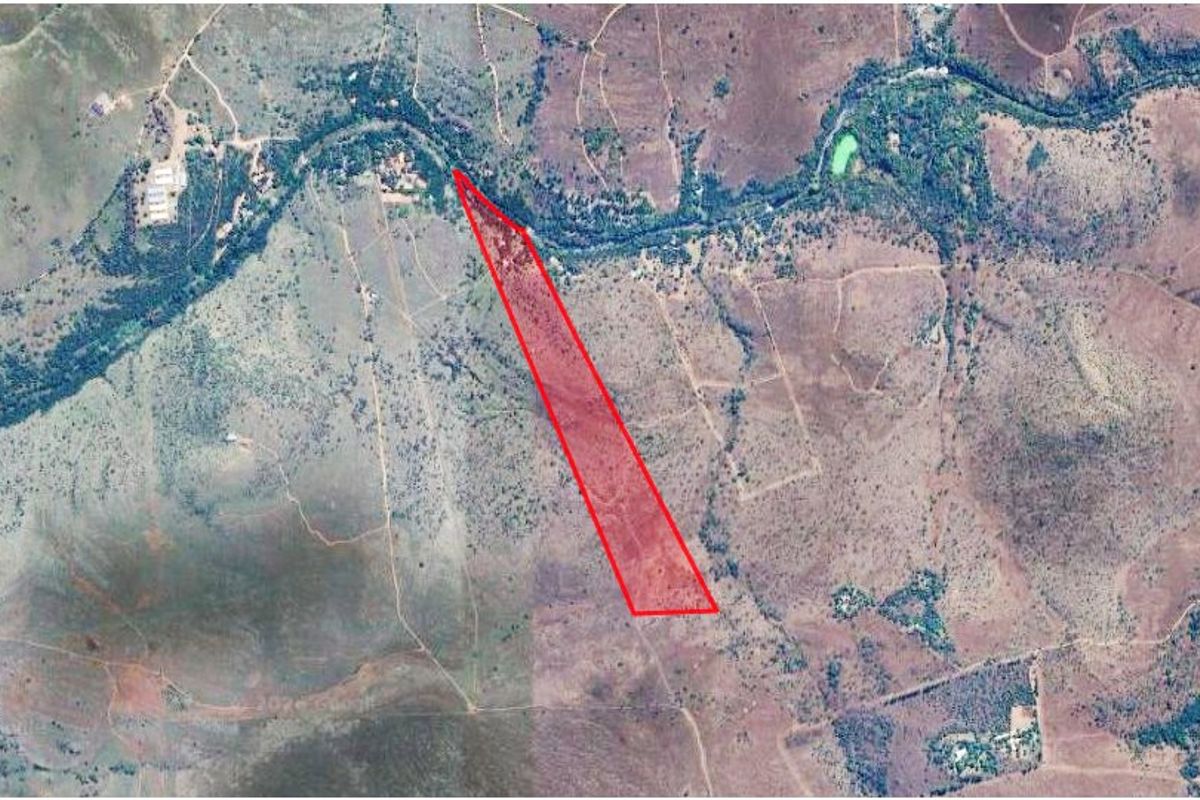 Aerial view of a large farm property featuring natural landscape, river frontage, and clearly marked boundary lines.
