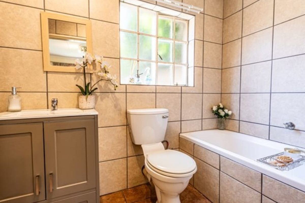 A functional bathroom featuring a vanity cabinet, toilet, and bathtub with neutral wall and floor tiling.