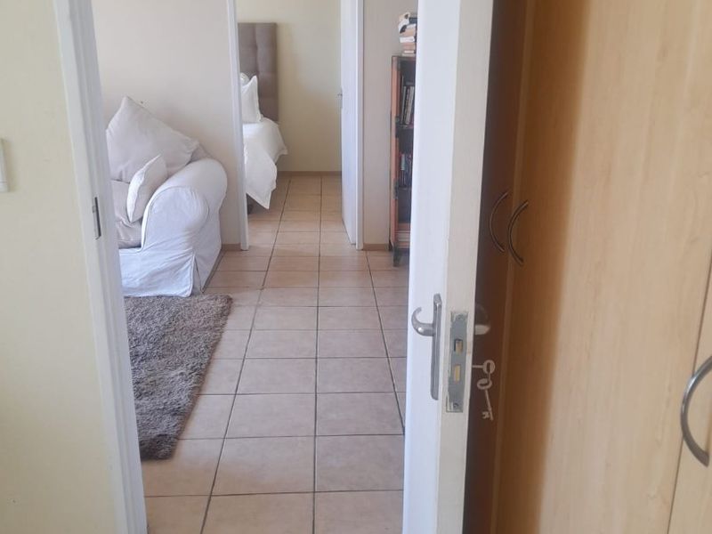 A tiled hallway providing access to living and bedroom areas, featuring built-in cupboard storage.