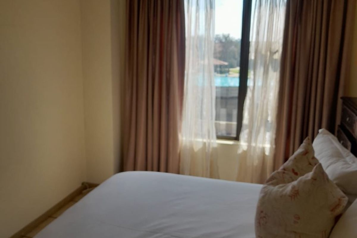 A bedroom featuring a window with curtain tracks, offering natural light and a view of the outdoor pool area.