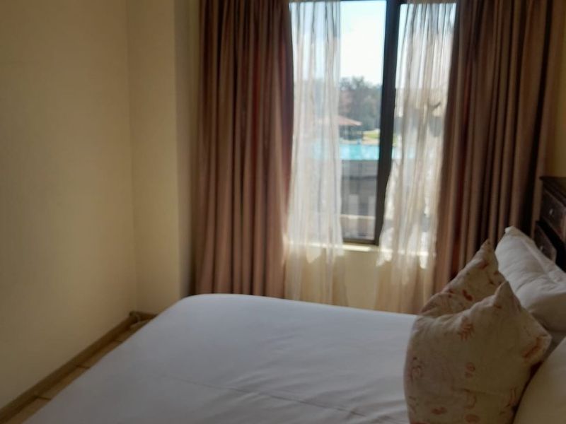 A bedroom featuring a window with curtain tracks, offering natural light and a view of the outdoor pool area.