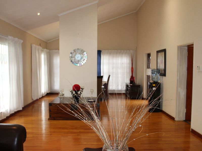 Spacious open-plan living area featuring high vaulted ceilings, warm hardwood flooring, and abundant natural light through multiple windows.