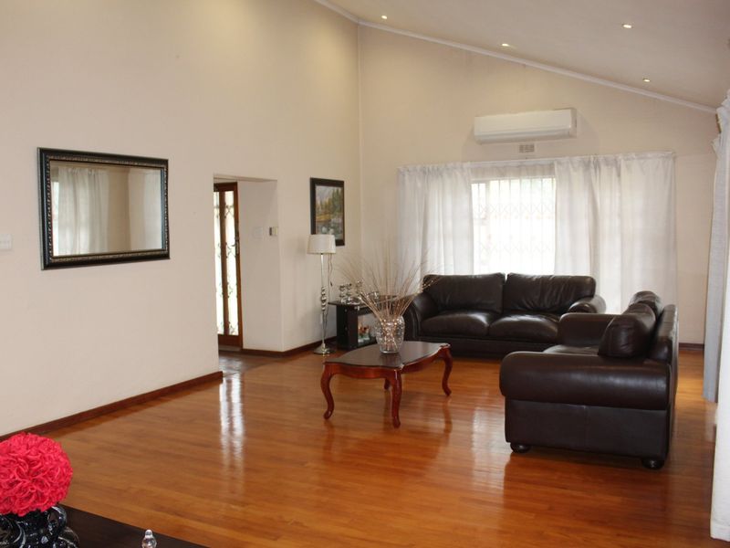 Spacious living room featuring high vaulted ceilings, polished hardwood flooring, and a wall-mounted air conditioning unit.
