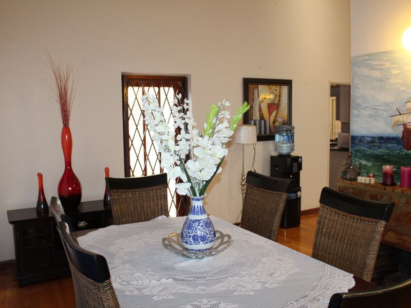 Dining room featuring hardwood flooring, a security gate, and a stone fireplace surround.