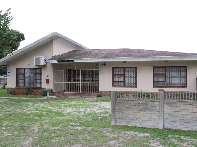 Front elevation of a single-story house featuring a tiled roof, security bars on windows, and a concrete boundary wall.