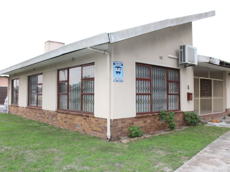 Front exterior view of a single-story house featuring a brick base, security bars on windows, and an installed air conditioning unit.