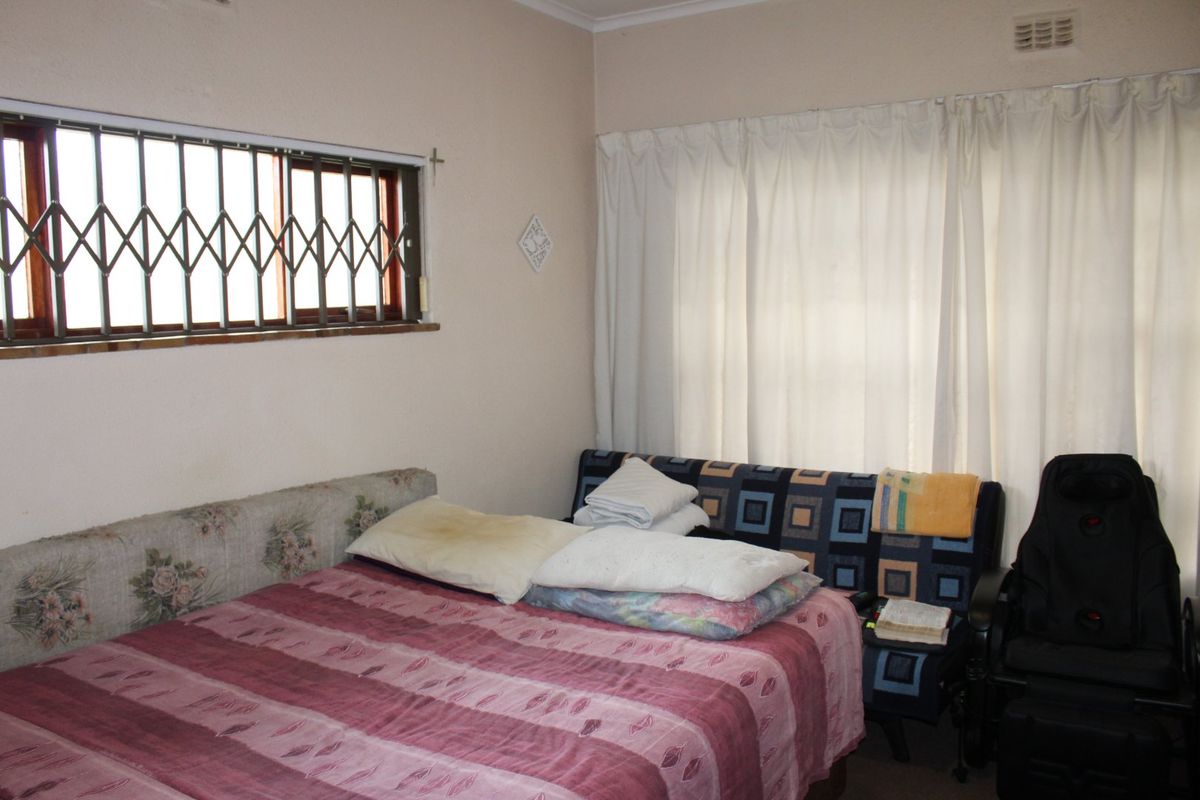 A functional bedroom featuring a sliding window with a security gate and a built-in ventilation grille.