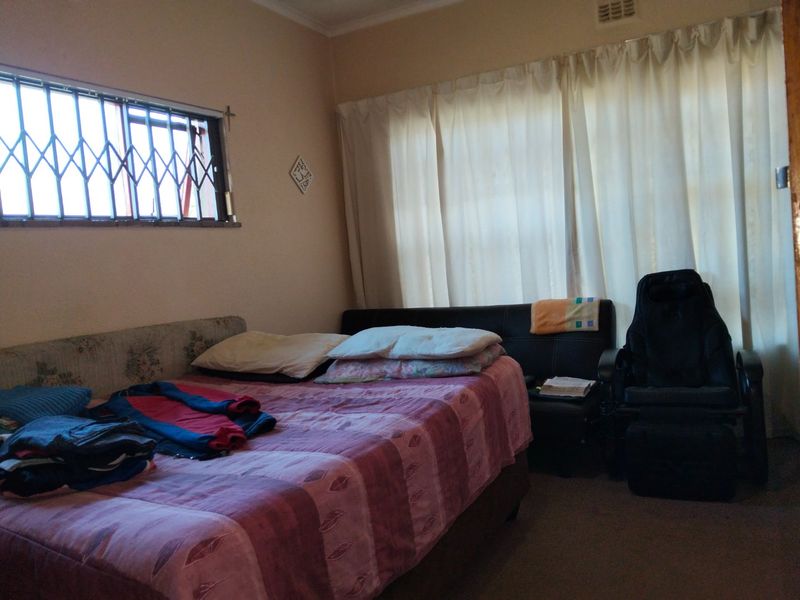 A functional bedroom featuring a window with a security gate and neutral wall finishes, offering a blank canvas for potential interior updates.