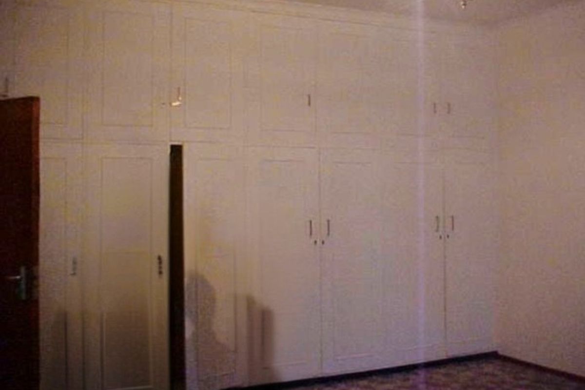 A bedroom featuring extensive floor-to-ceiling built-in cupboards providing ample storage space.