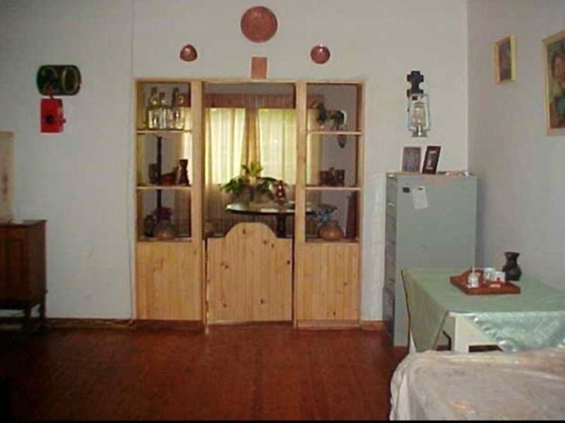 A living area featuring built-in wooden shelving and a timber room divider, with wooden flooring throughout.