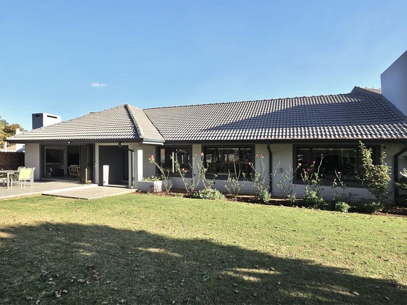 Rear view of the house featuring a tiled roof, concrete patio area, and large sliding glass doors opening onto a well-maintained garden.