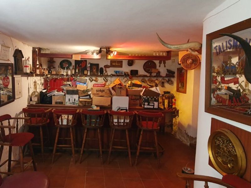 A dedicated home bar area featuring a built-in counter and tiled flooring, currently requiring cosmetic updates and wall repairs.