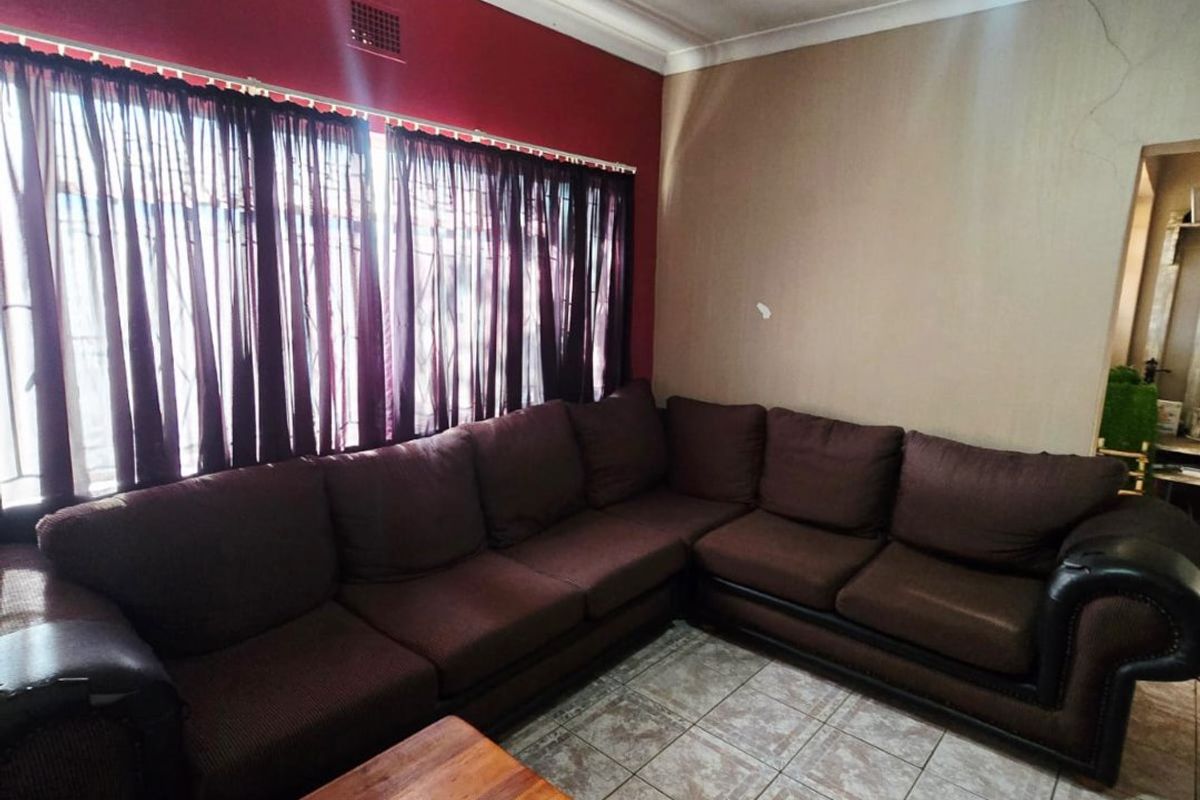 Living room featuring ceramic tiled flooring, a ceiling fan, and visible signs of ceiling and wall maintenance requirements.
