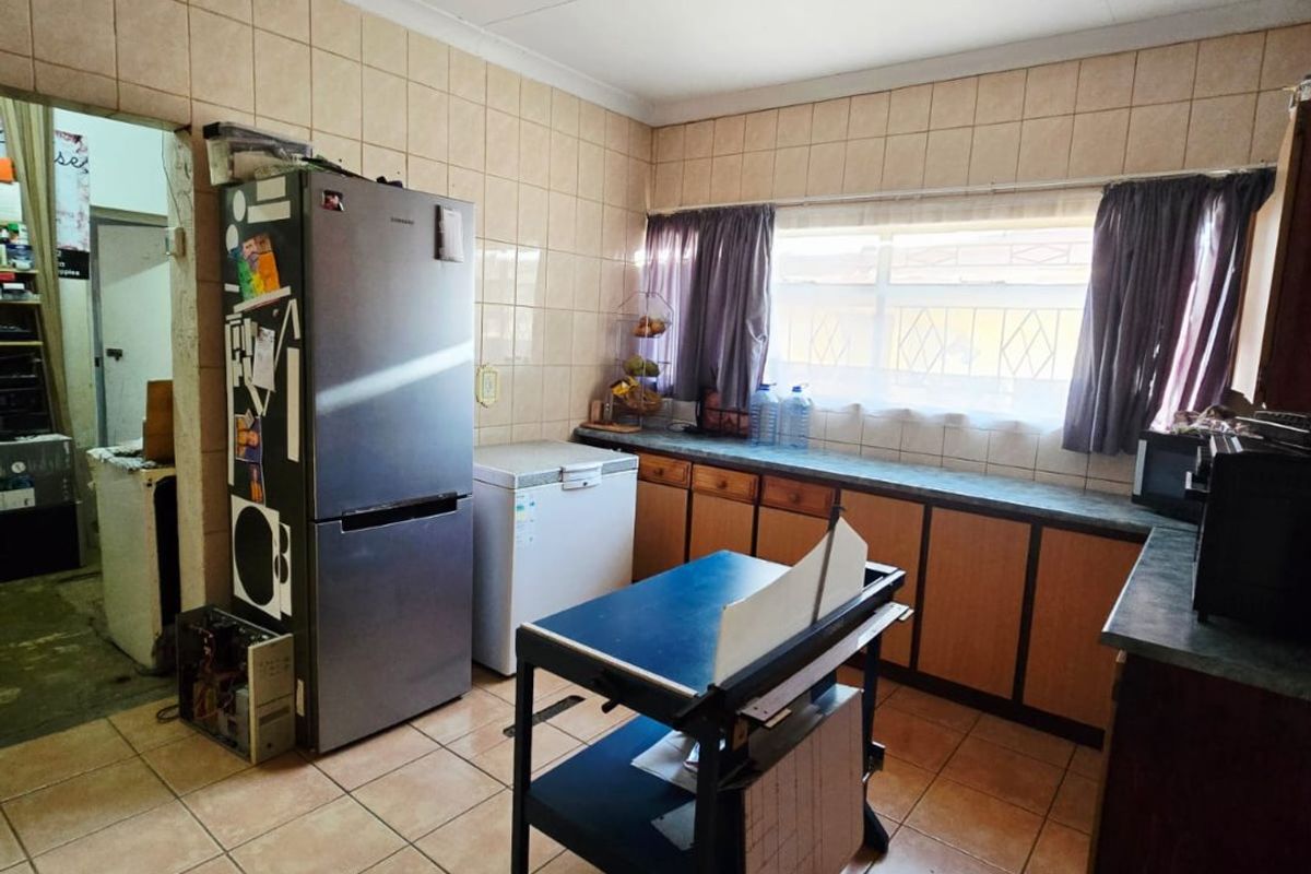 A dated kitchen featuring tiled walls and flooring, built-in cabinetry, and laminate countertops, offering significant potential for a modern renovation.