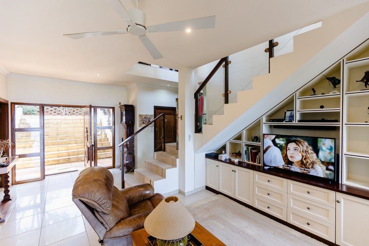 Spacious living area featuring custom built-in cabinetry under the staircase, tiled flooring, and direct access to an outdoor patio area.