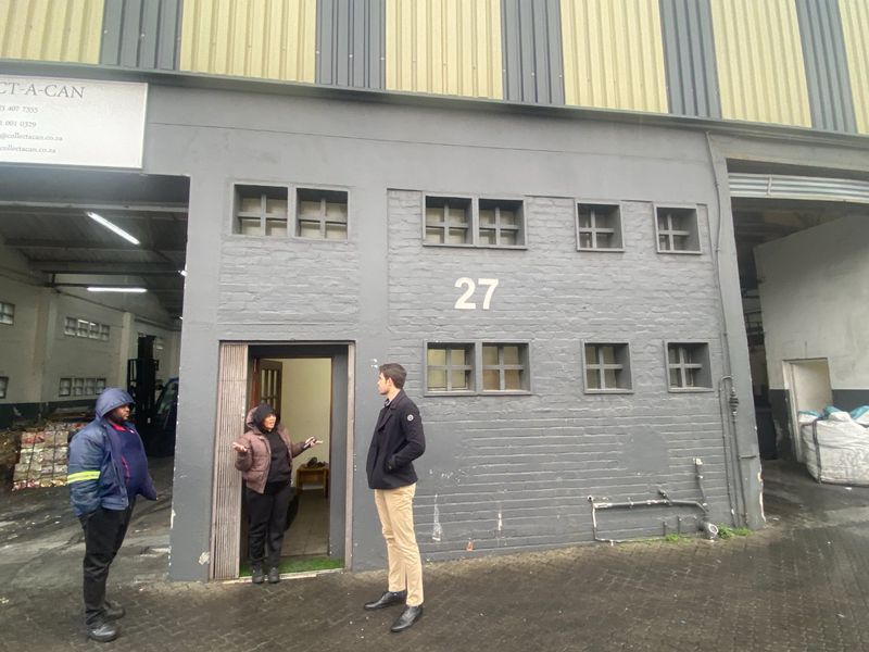 Front elevation of an industrial warehouse unit featuring painted brickwork, metal cladding, and multiple small windows.