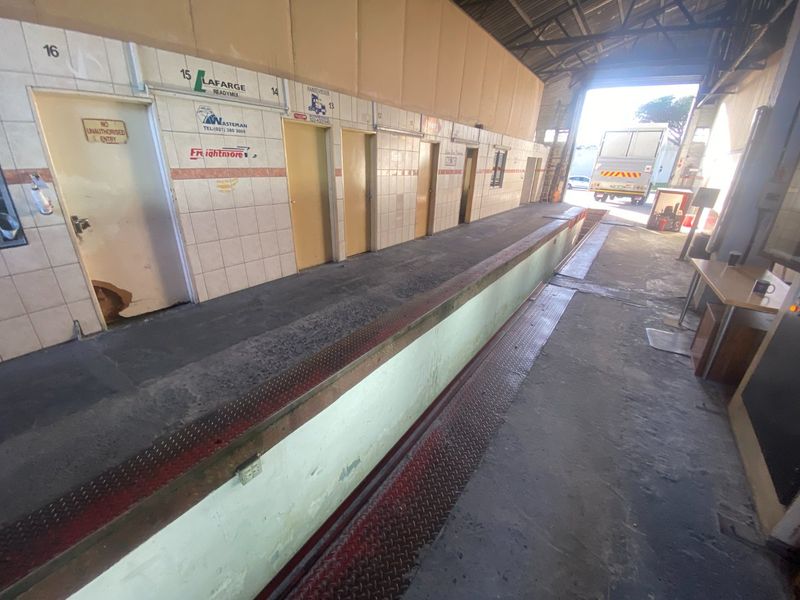 Industrial utility space featuring a built-in weighbridge, tiled wall finishes, and direct access via a large roller shutter door.