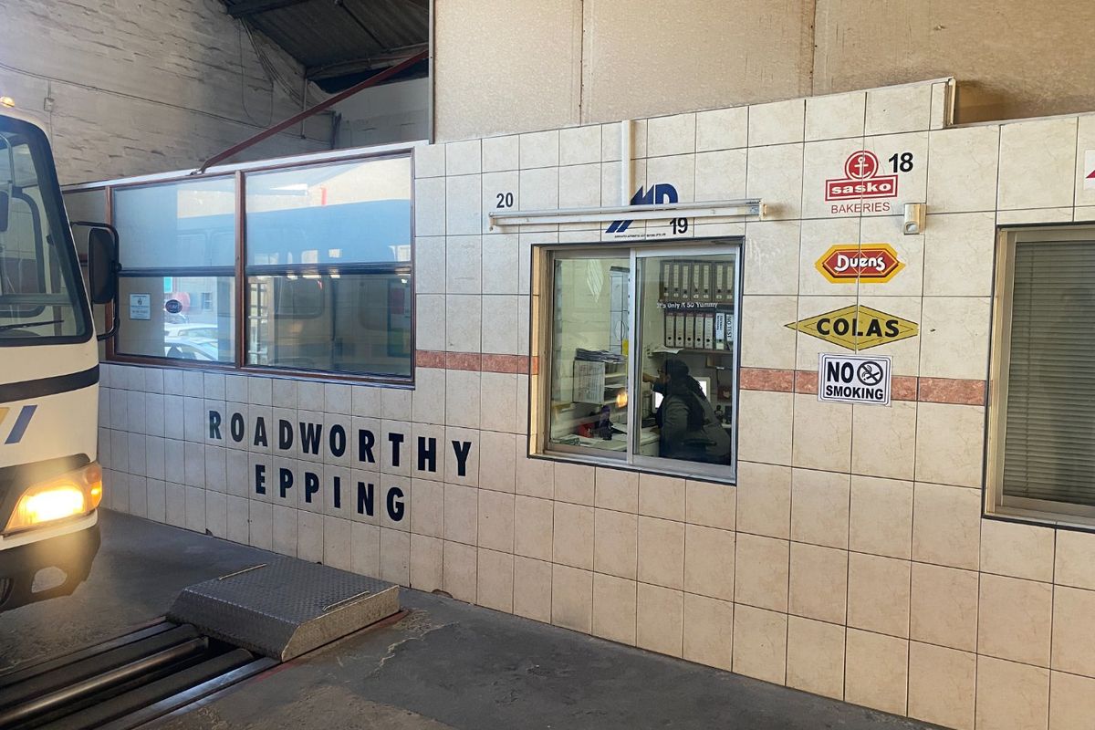 Industrial inspection office featuring tiled wall cladding and a service window within a large warehouse facility.